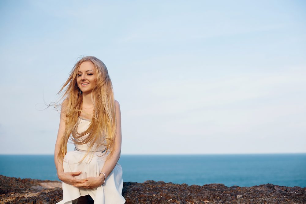 Portrait of happy smiling woman on the beach. Smiling Pretty blonde girl posing on beautiful wild beach